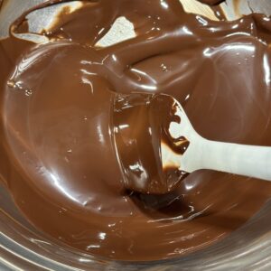 Fully melted and glossy Lindt Excellence 70% cacao dark chocolate on a double-boiler to prepare sab pastries dark chocolate whipped ganache